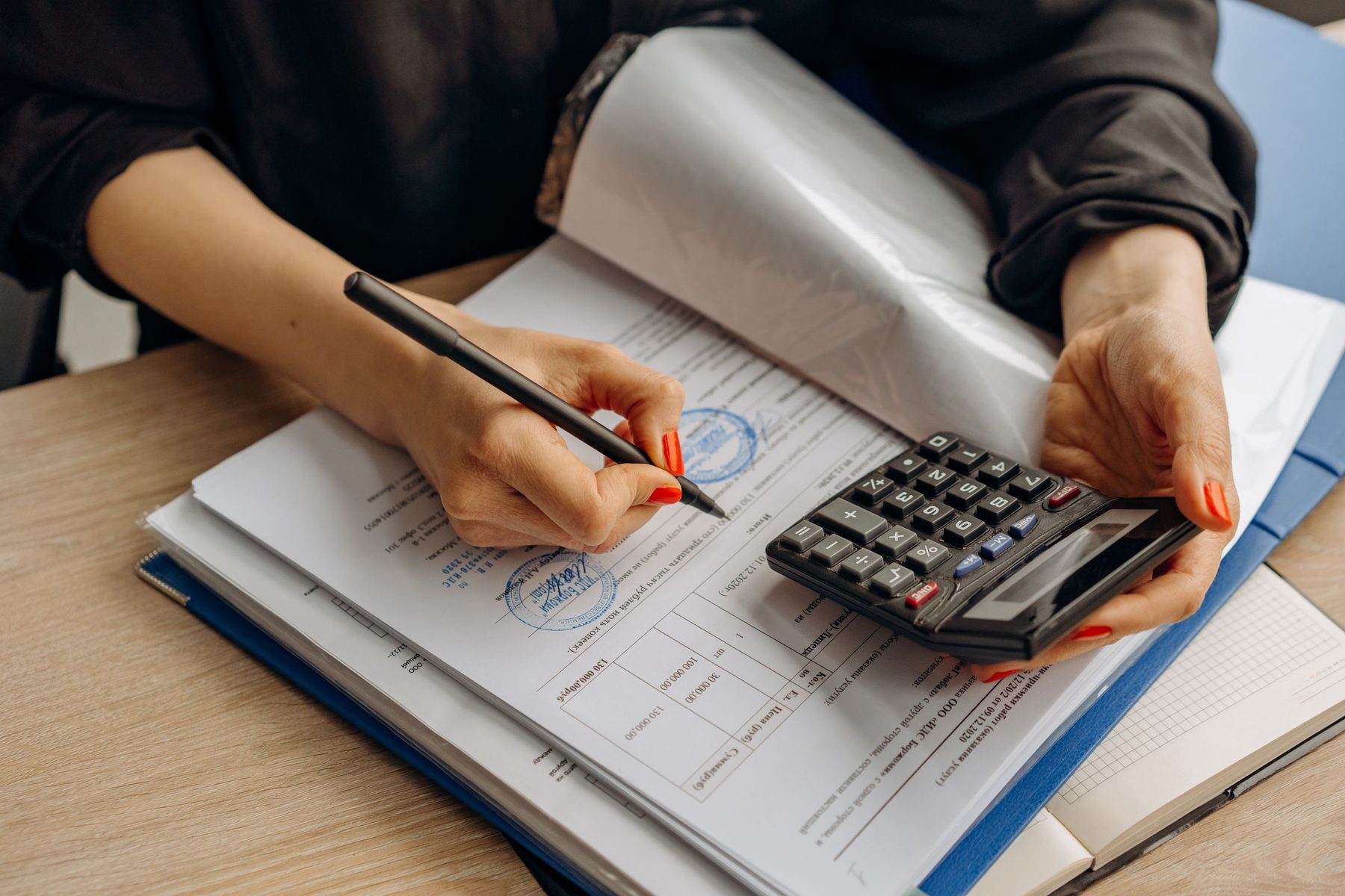 An accountant checking a set of books by hand with a calculator and pen