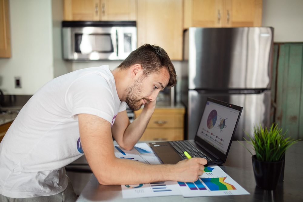 A founder with his head in his hand, going over cash flow charts on his laptop