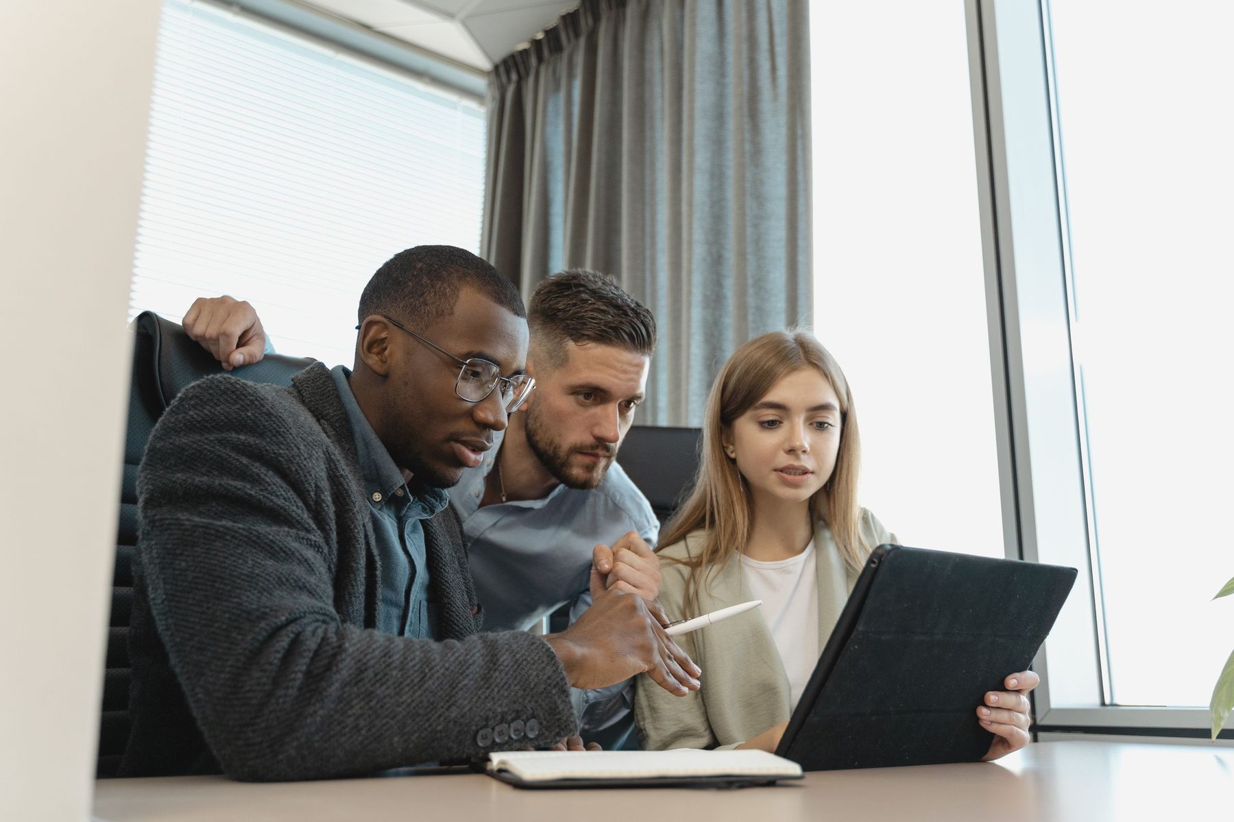 Three colleagues working through a problem together on a tablet