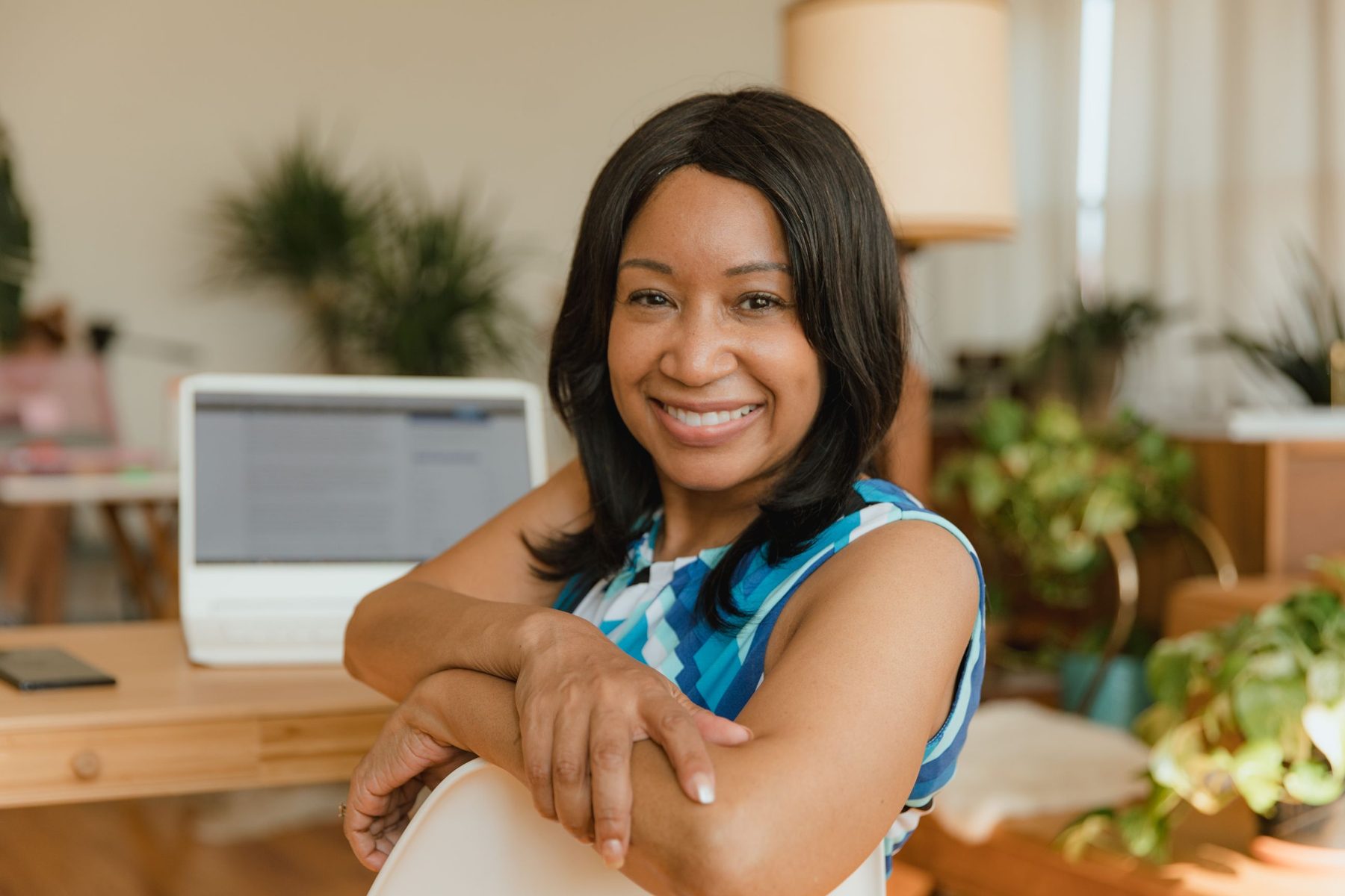 A smiling business owner at her desk, her laptop open behind her