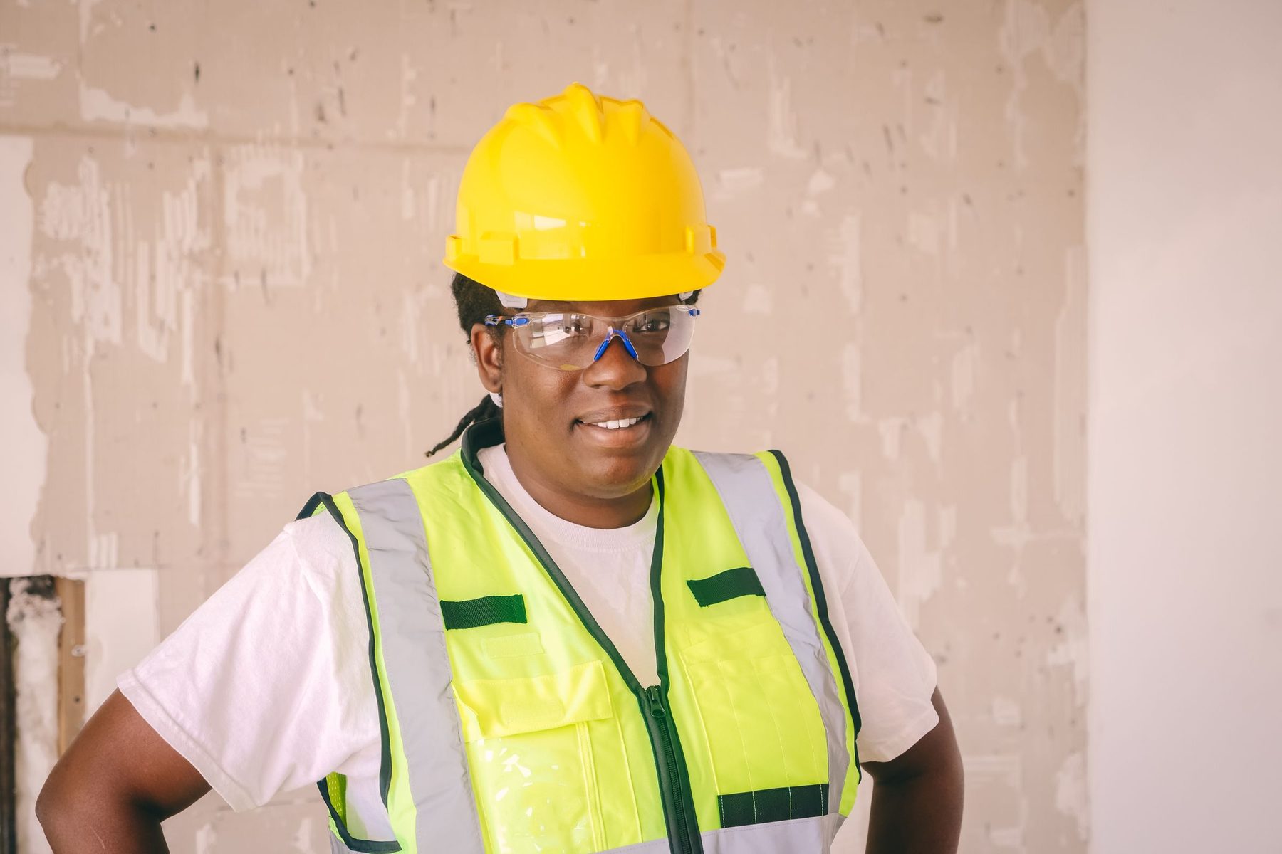 A smiling construction manager in a hard hat and safety vest on site