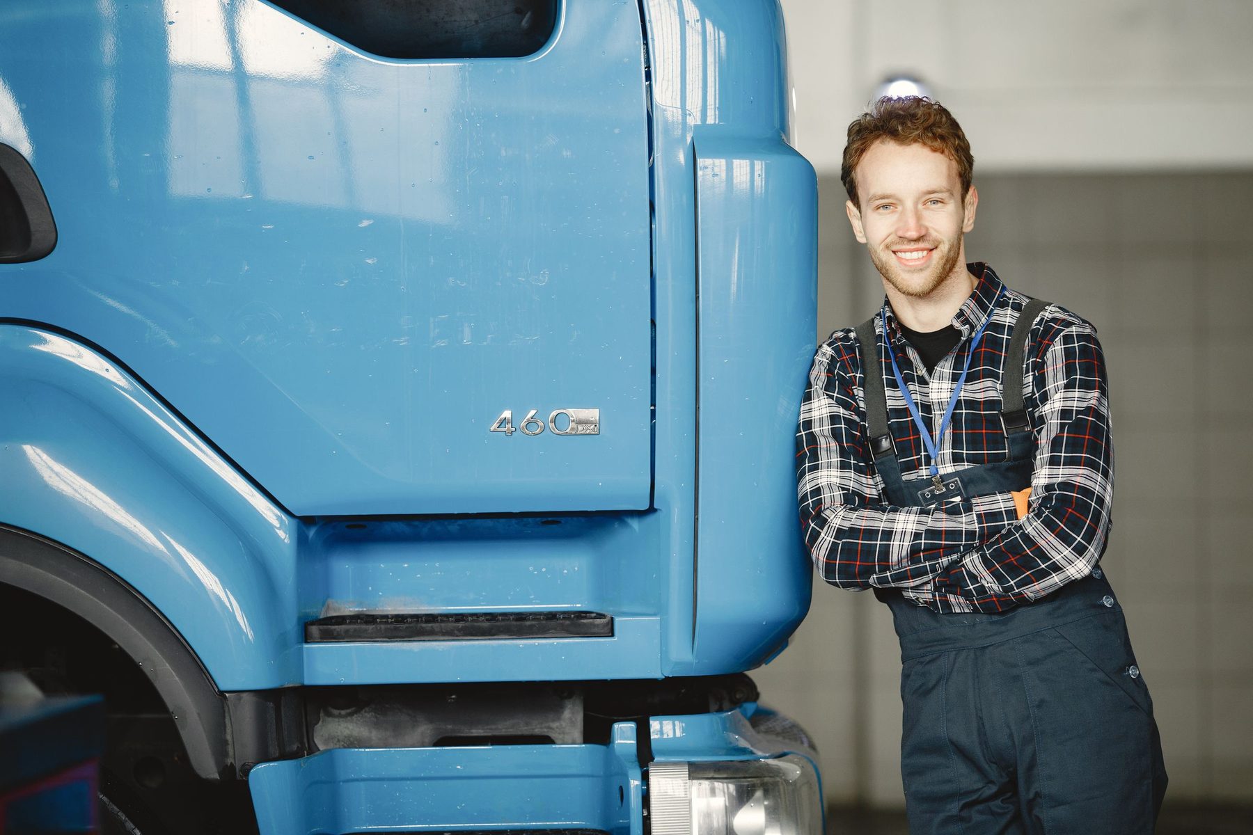 A smiling truck owner leaning on his truck in the workshop