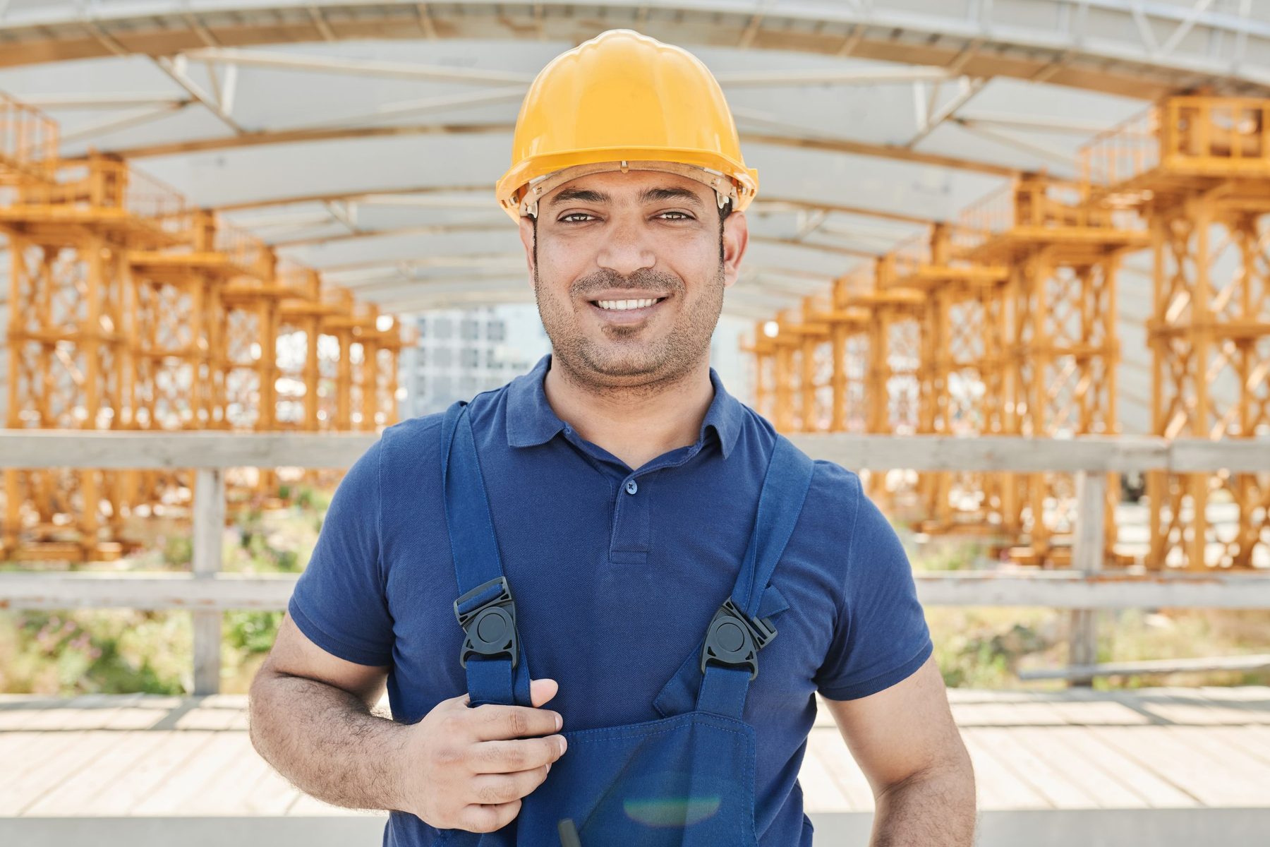 A smiling construction contractor in a hard hat on site